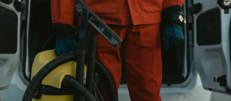 a janitor holding a vaccum cleaner