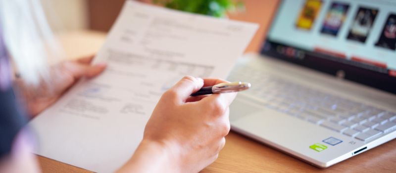 a person holding a document and a pen