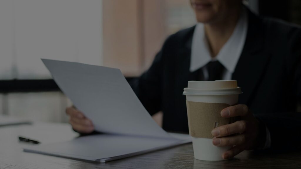 a person holding a coffee and a piece of paper