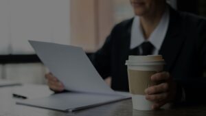 a person holding a coffee and a piece of paper