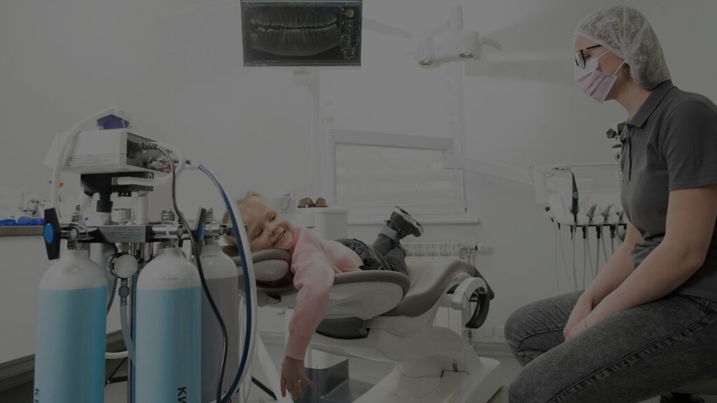 smiling child in a dental chair with a friendly dentist